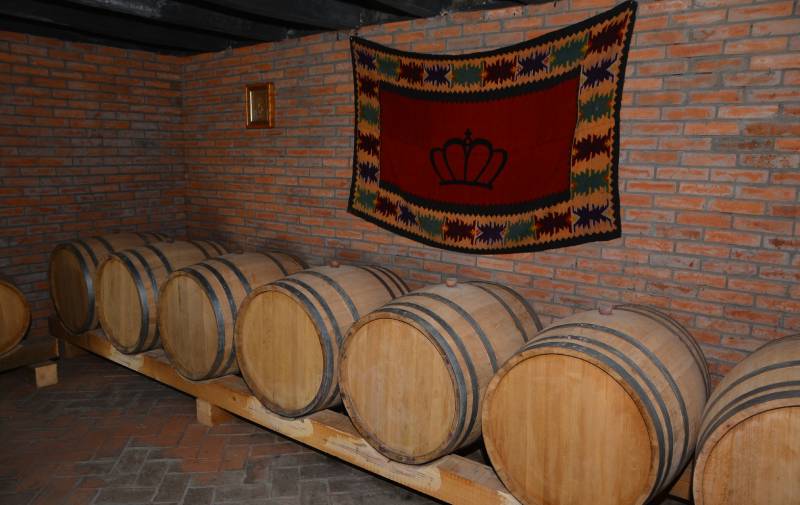Slika buradi u kojima se čuva vino iznad kojih je okačeno ćbe sa logotipom vinarije